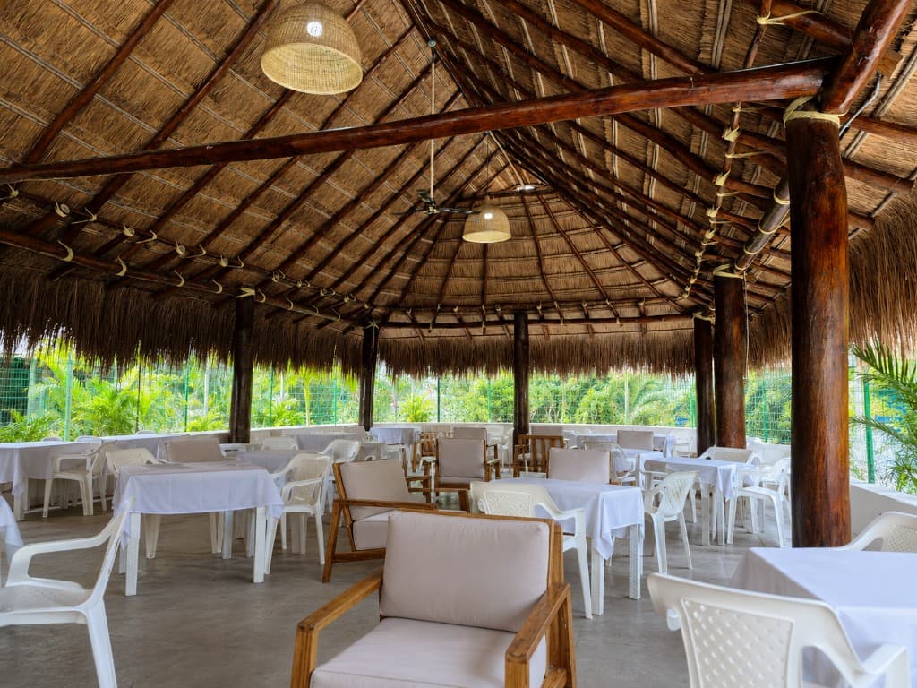 Kiosko social con techo de palma y mesas para eventos